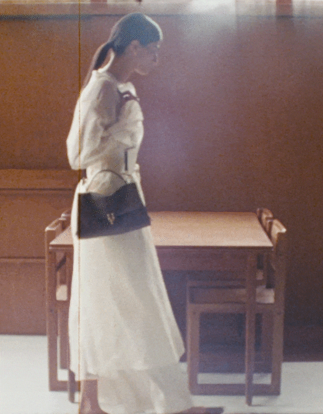 an image of a woman in a white suit and black gloves