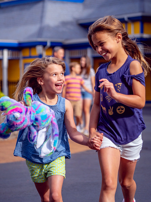 Two girls holding hands and running in the main gate of Lake Compounce
