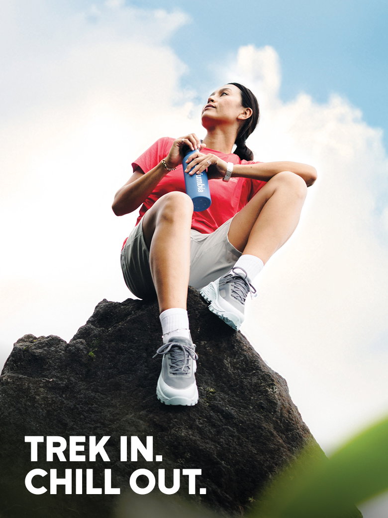 Trek in. Chill out. Woman sitting on a rock in hiking gear.