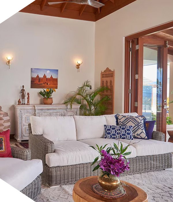 Airy living area with wicker sofa, patterned pillows, wood ceiling, console table, and glass doors.