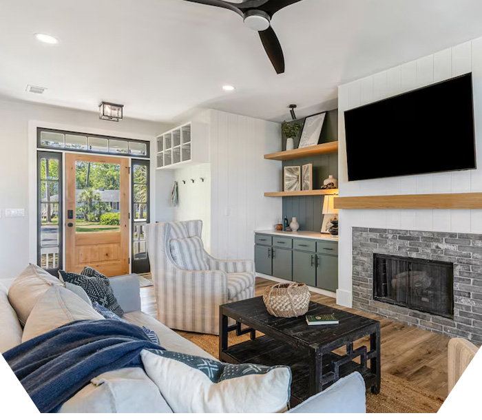 Bright living room with couch, armchair, coffee table, fireplace, and wall-mounted TV.
