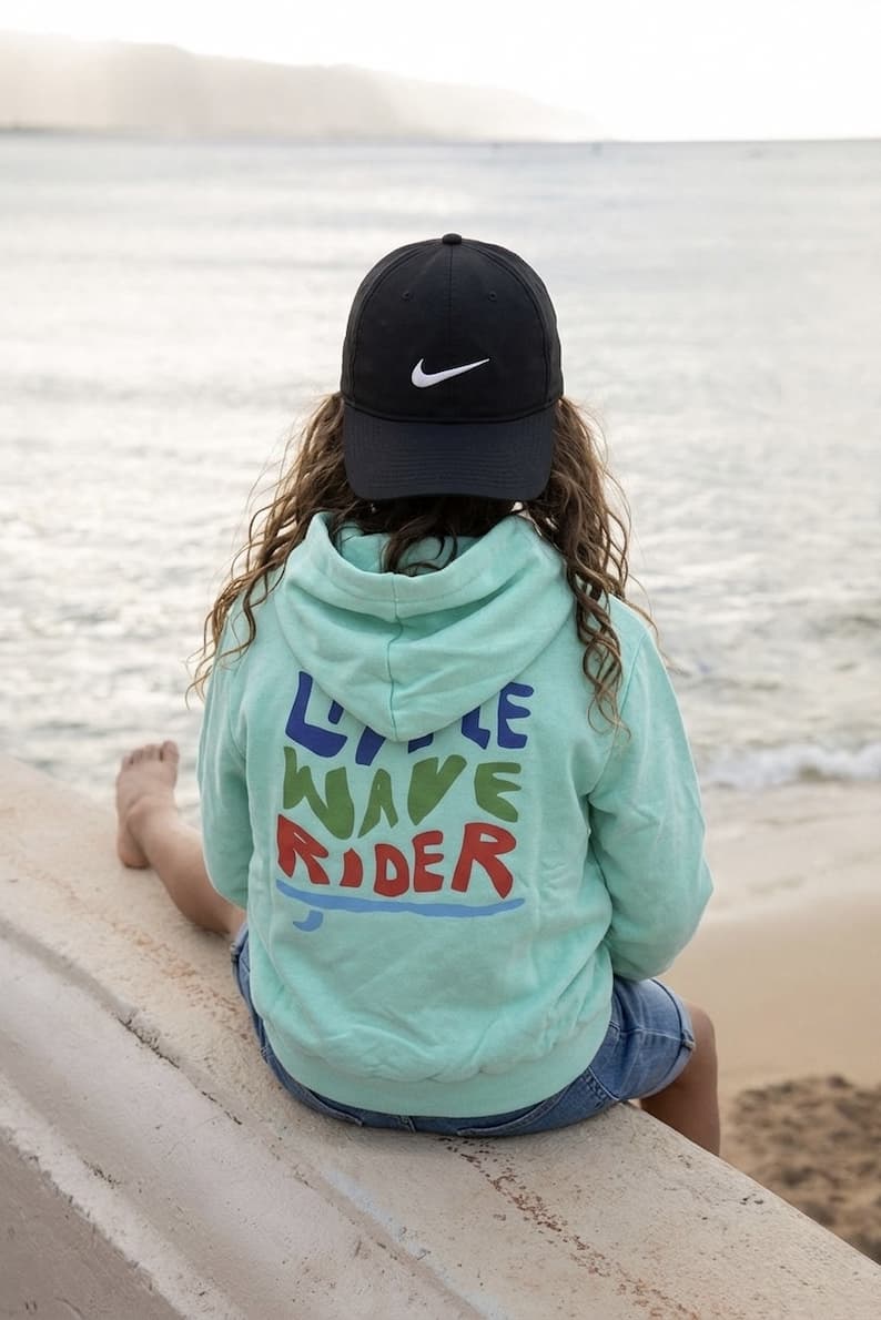 blue kids hoodie jumper sitting at beach
