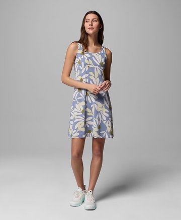 A woman wearing a grey and tan floral dress against a grey background.