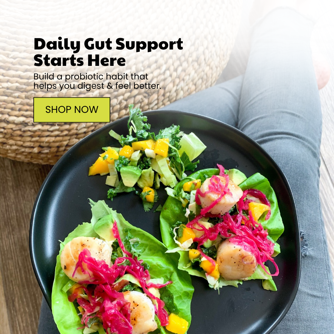 Overhead view of a person relaxing with a plate of scallop lettuce wraps, mango salsa, and kale salad, promoting gut health.