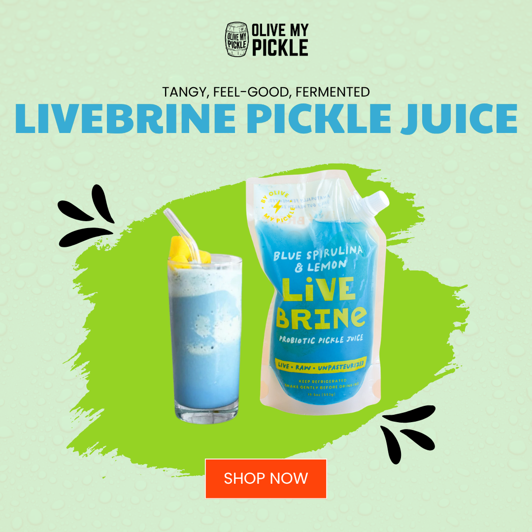 Olive My Pickle LiveBrine Blue Spirulina & Lemon probiotic pickle juice pouch next to a glass of the blue drink with a straw and mango garnish, on a green backg