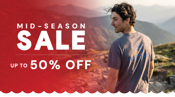 MID-SEASON SALE: UP TO 50% OFF. A man looks out over a mountain range, wearing Arc'teryx Men's Kragg SL Cotton Bird Word Short-Sleeve T-Shirt in DK Stratus/Fluidity