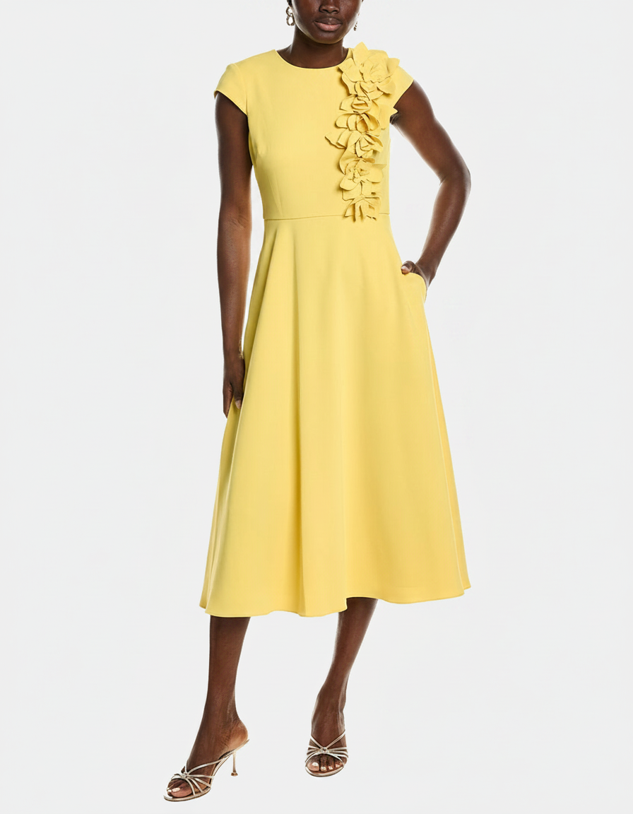 Woman in a yellow dress with floral embellishments and metallic heels.