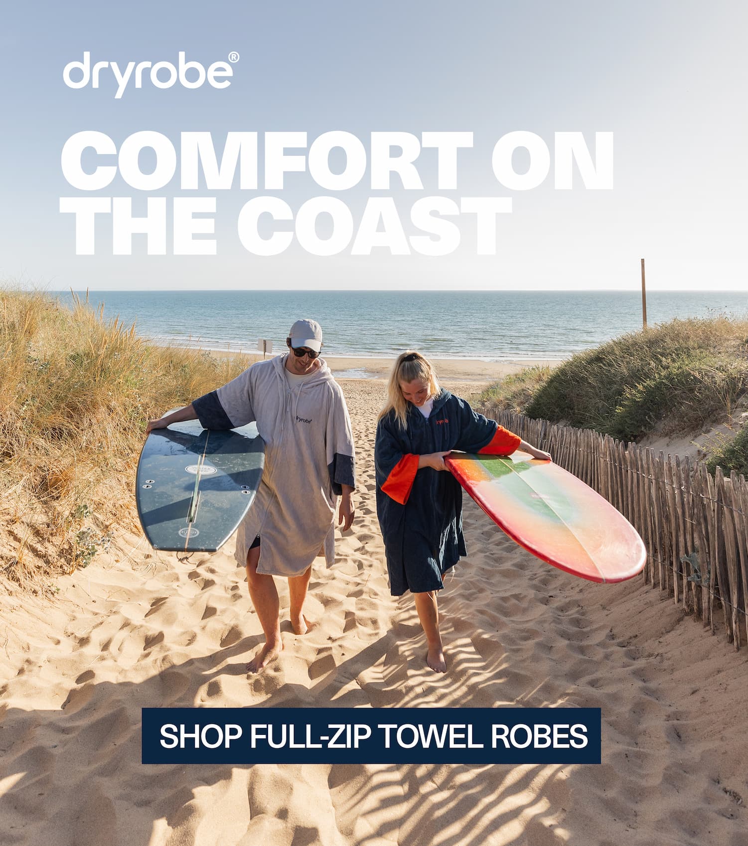 Two friends on the beach carrying surfboards while wearing Full-Zip Towel Robes