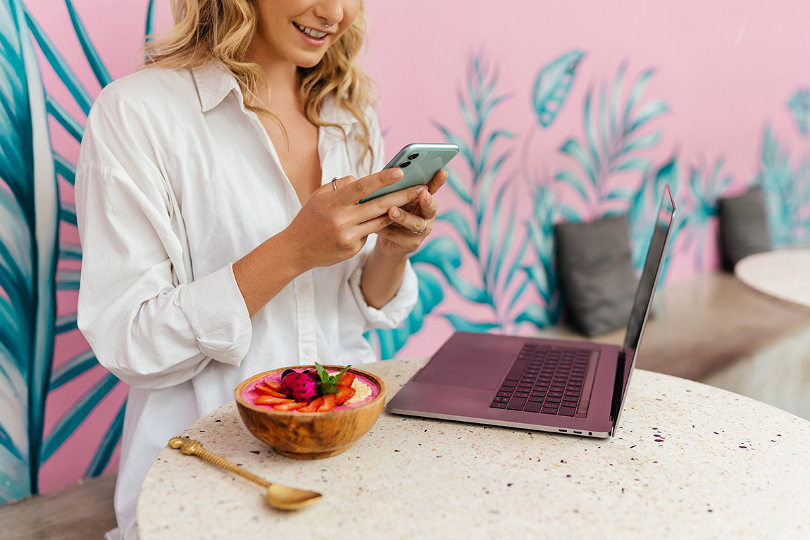 Woamn eating an acai bowl while shopping online