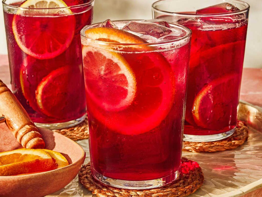 Three glasses of tinto de verano next to a bowl of sliced lemons and oranges.