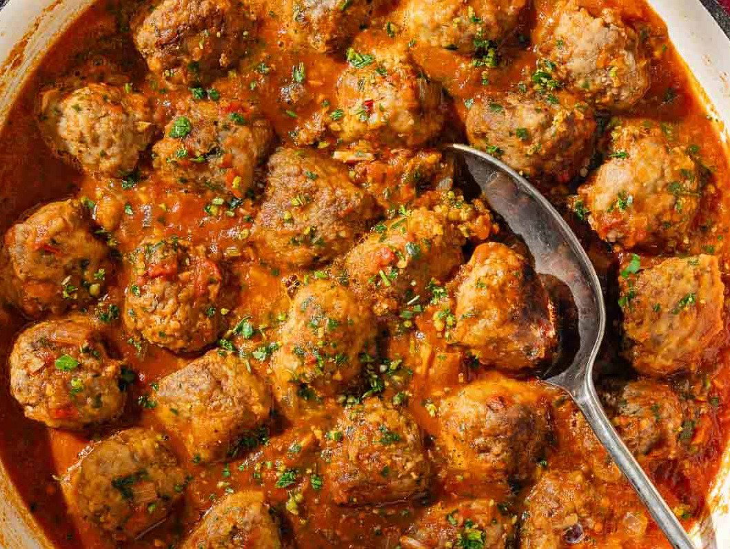 Spanish meatballs in a skillet with a serving spoon.