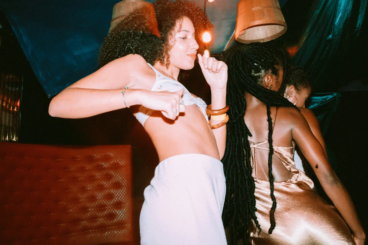Two women at a party with dim lighting and colorful decor.