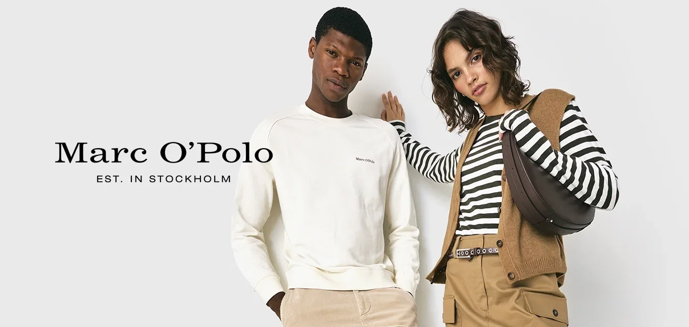 Deux adultes adossés à un mur blanc, un homme en sweat crème et pantalon, une femme en haut rayé, jupe beige, gilet, bottes noires, portant un sac.