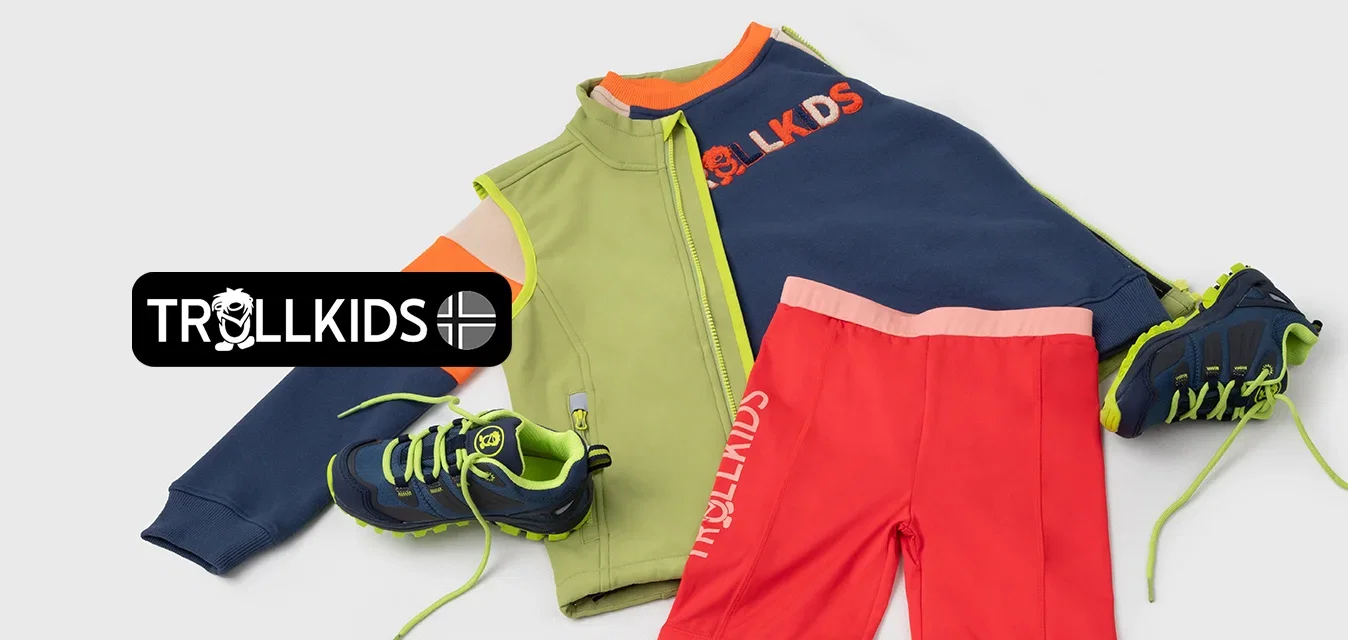 Une tenue de sport colorée qui comprend une veste verte et marine, un short rouge et des chaussures noires avec des lacets vert fluo, affichant des textures et des motifs variés.