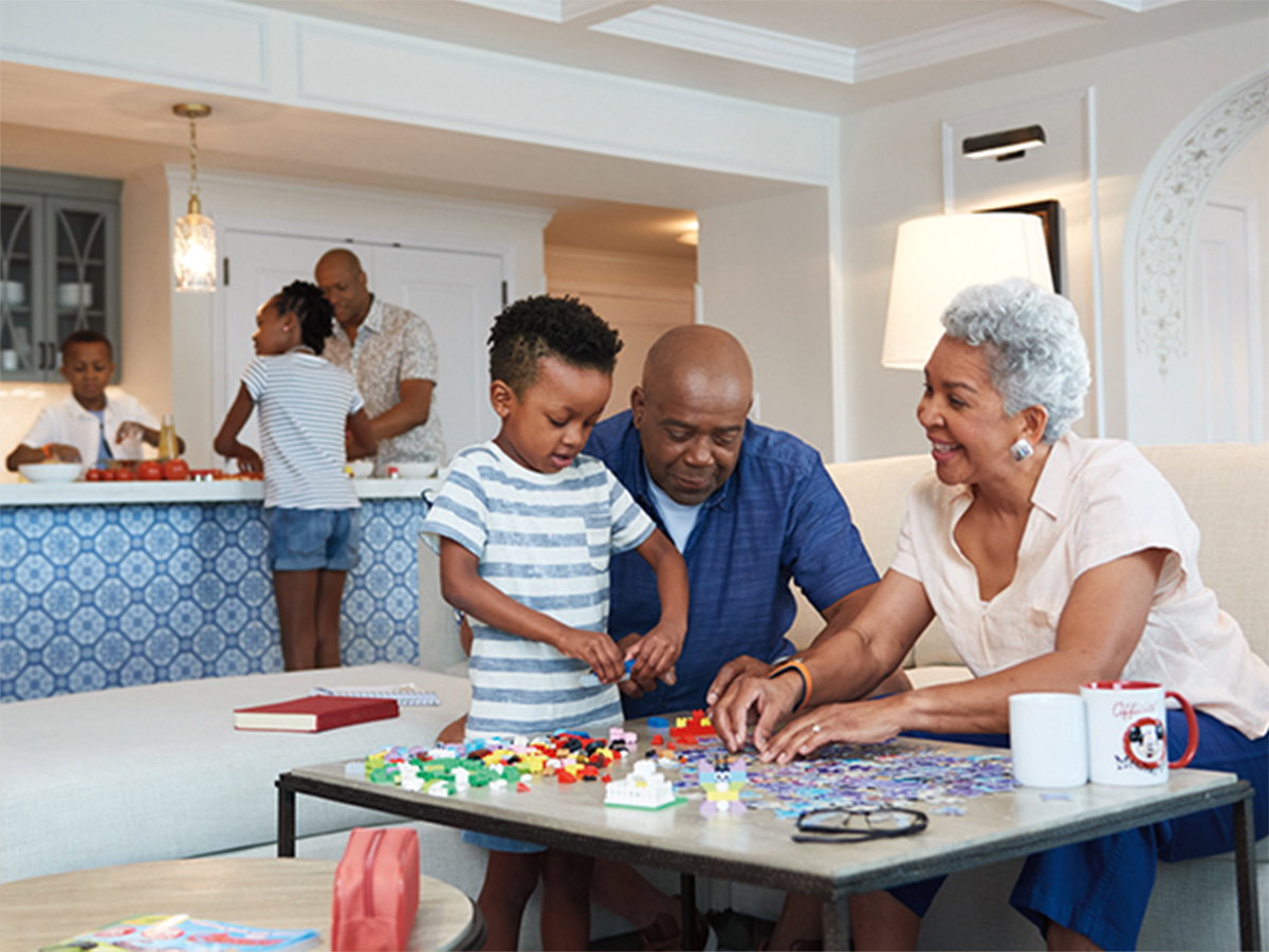 Grandparents build Legos with their grandchild inside their Three-Bedroom Grand Villa at Disney's Riviera Resort.