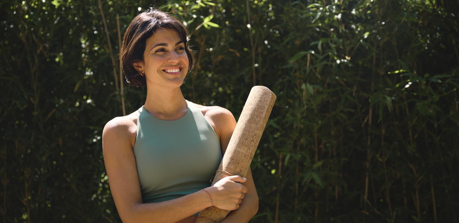 Woman in athleisure standing outside holding a yoga mat. Check out our Empowered blog.