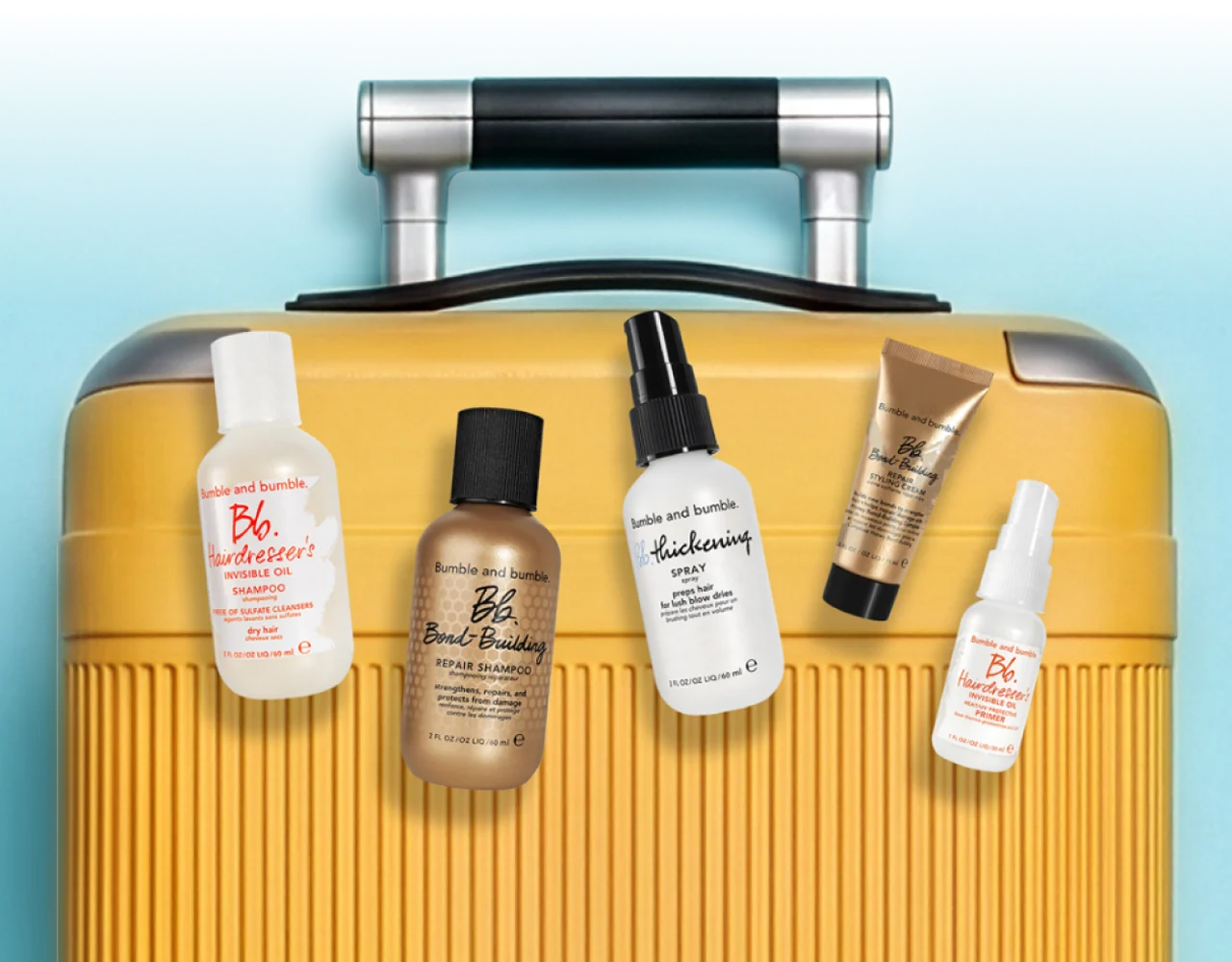 Selection of Bumble and bumble minis on a bright yellow suitcase, shot overhead