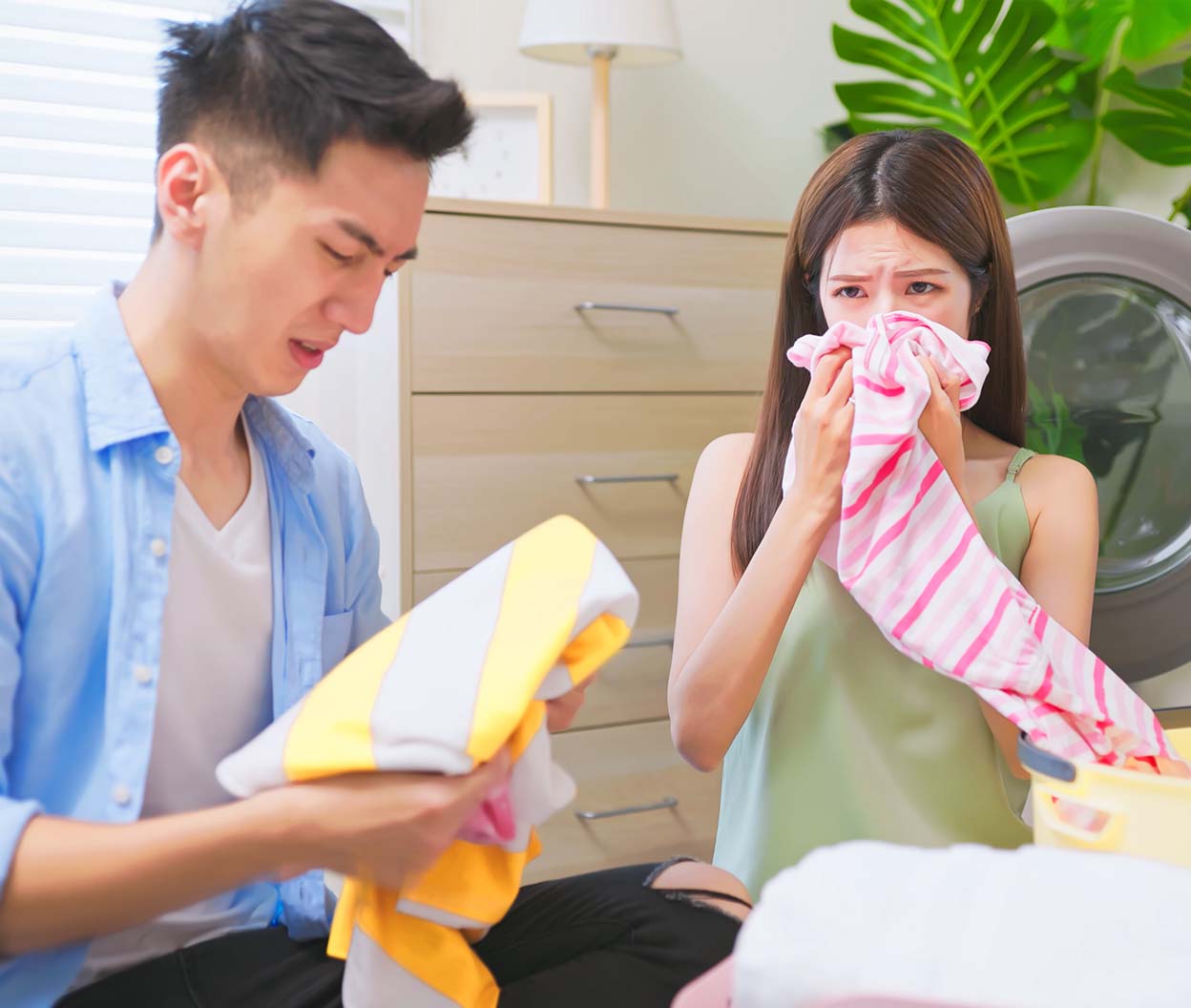 People reacting to smelly laundry near a washing machine