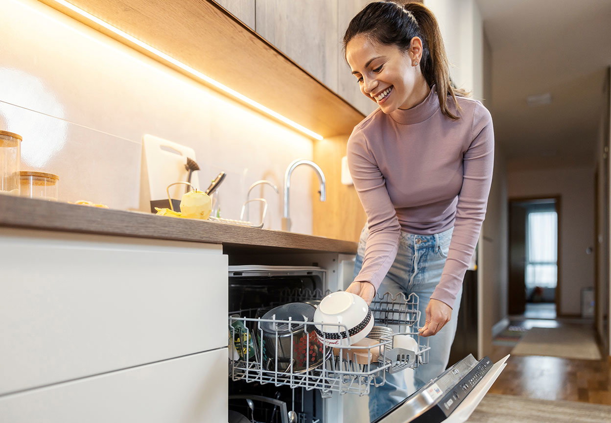 Woman unloading clean dishes from a dishwasher