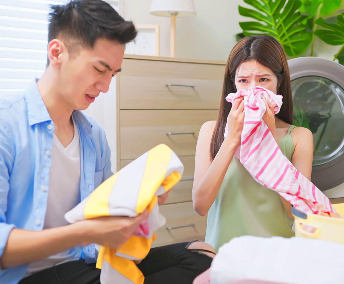 People reacting to smelly laundry near a washing machine