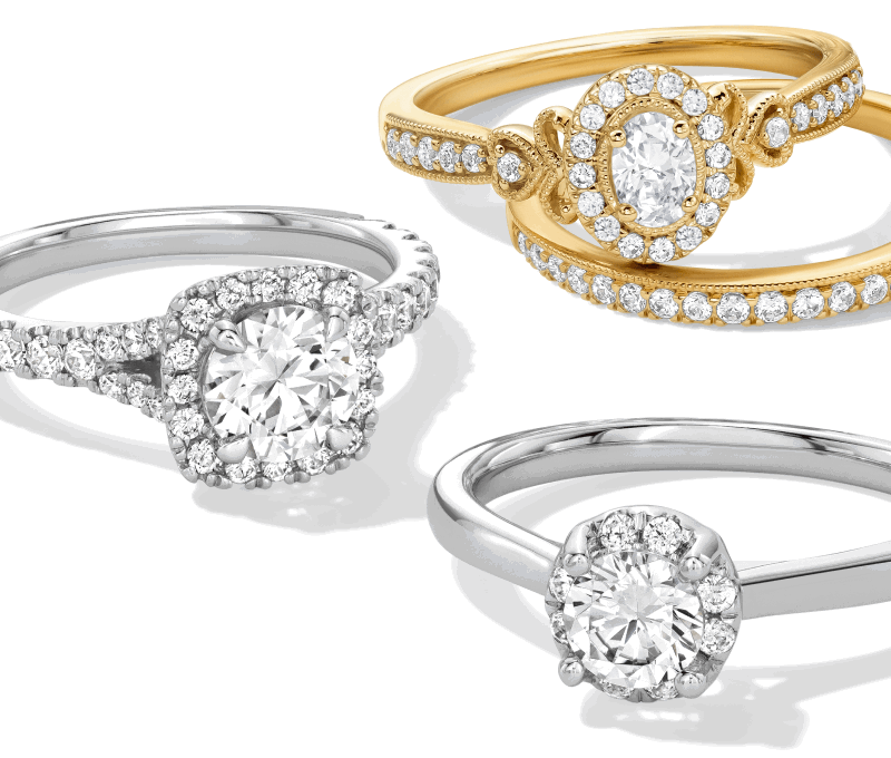 Assorted diamond engagement rings in white and yellow metal, featuring round and oval stones with halo and pavé bands.