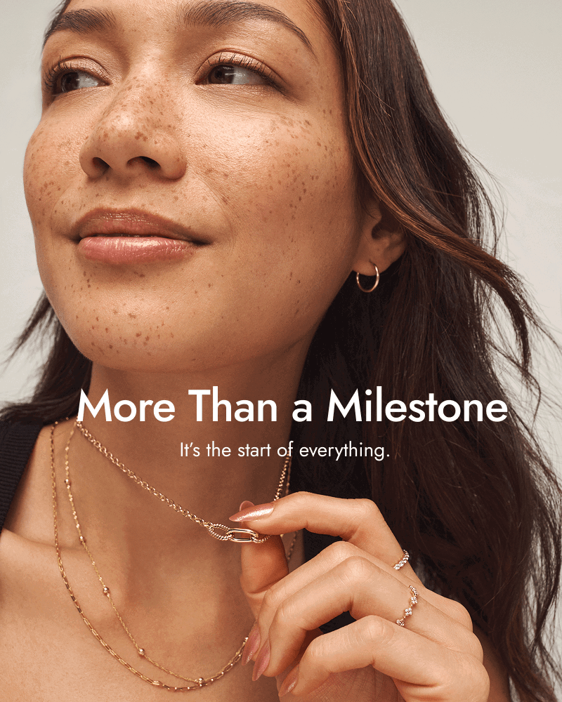 Woman wearing various fine yellow gold jewellery. More than a milestone, it’s the start of everything.