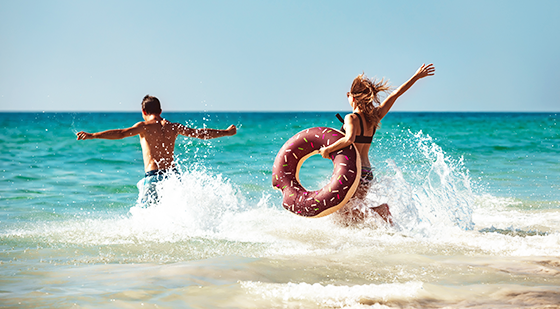 Paar plantscht mit buntem Schwimmring am Meer