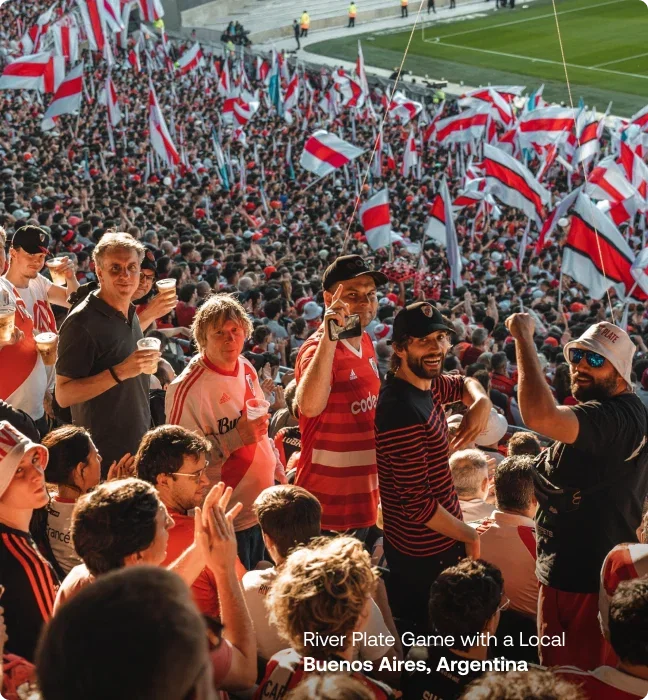 A crowded soccer stadium filled with fans waving red and white flags.