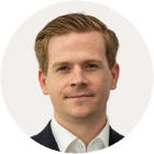 Headshot of Nick Eardley who has short light brown hair, and wears a white shirt with a dark suit jacket.