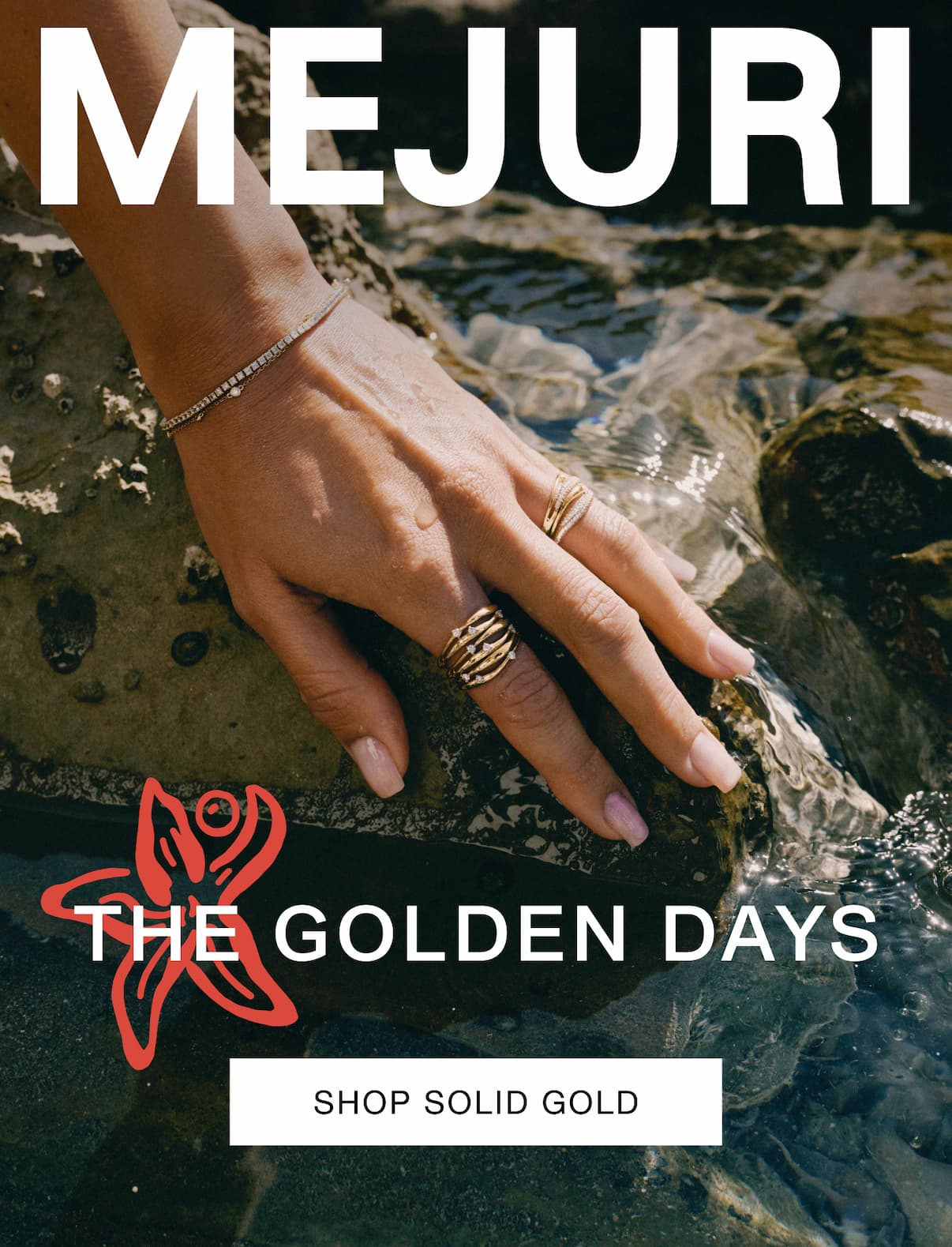 Hand resting on rocks near water wearing Mejuri gold rings and a diamond tennis bracelet — The Golden Days — Shop Solid Gold.