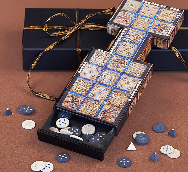 Playable set of The Royal Game of Ur with textured board and pieces displayed on a gift box. - Shop Now.