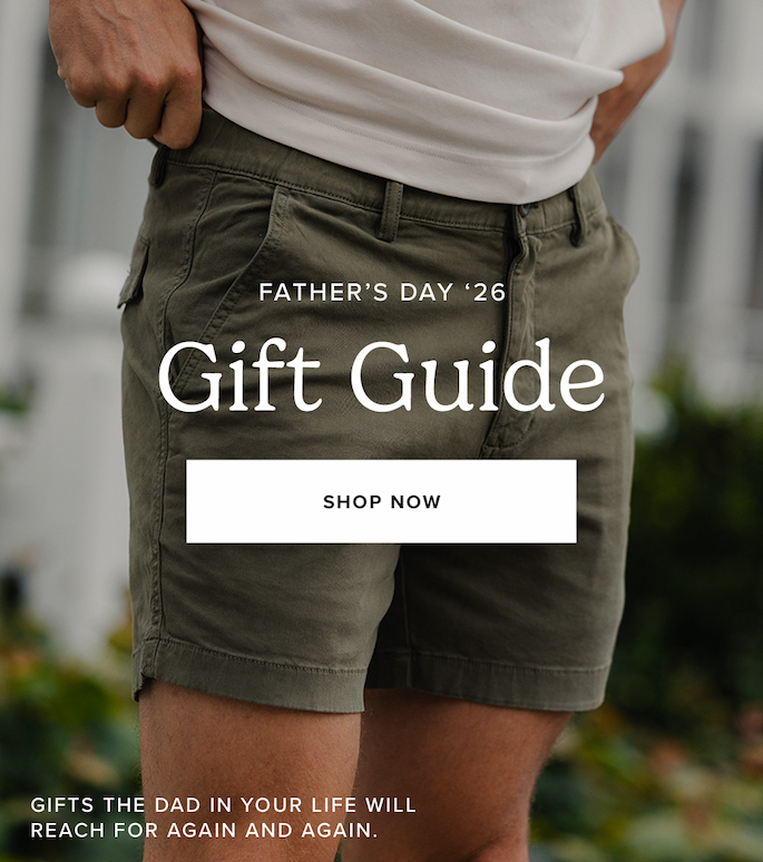 Close-up of a person wearing a white shirt and olive green shorts, with hands resting near the waistband. Text reads: "Father's Day '26 Gift Guide. Shop Now. Gifts the dad in your life will reach for again and again."