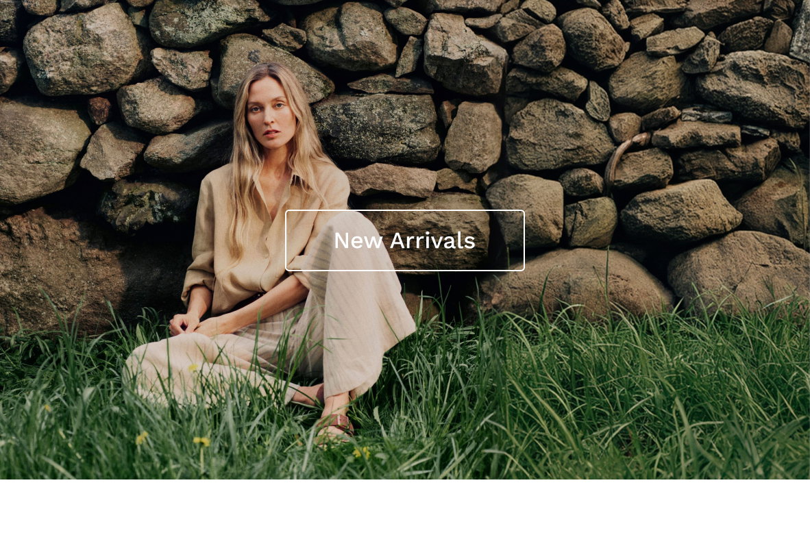 Image of a model in a neutral outfit sitting on grass.