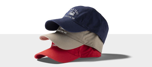 Three Crab Fest dad hats in red, tan, and blue stacked on top of each other.