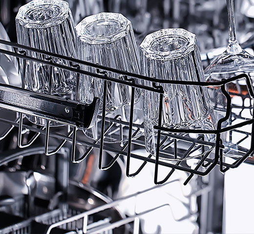 Clean glasses and stemware arranged upside down in a dishwasher rack after a wash cycle