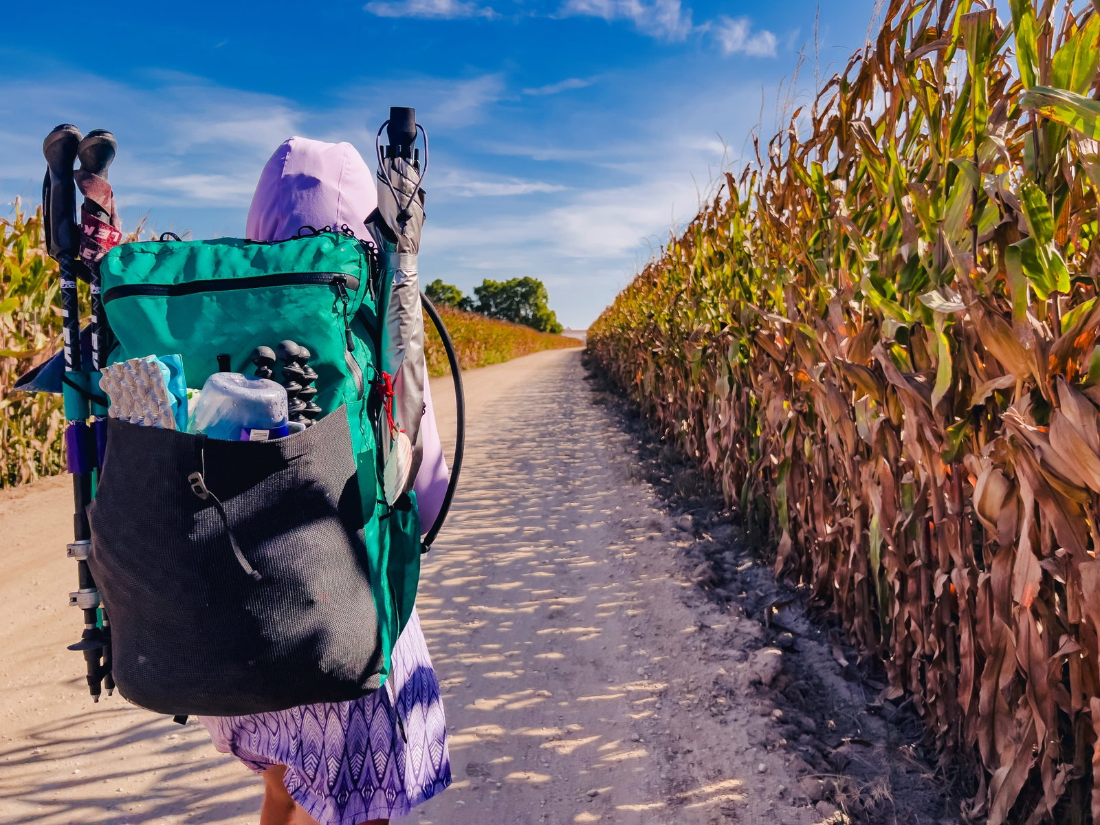 girl hiking in corn with backpack
