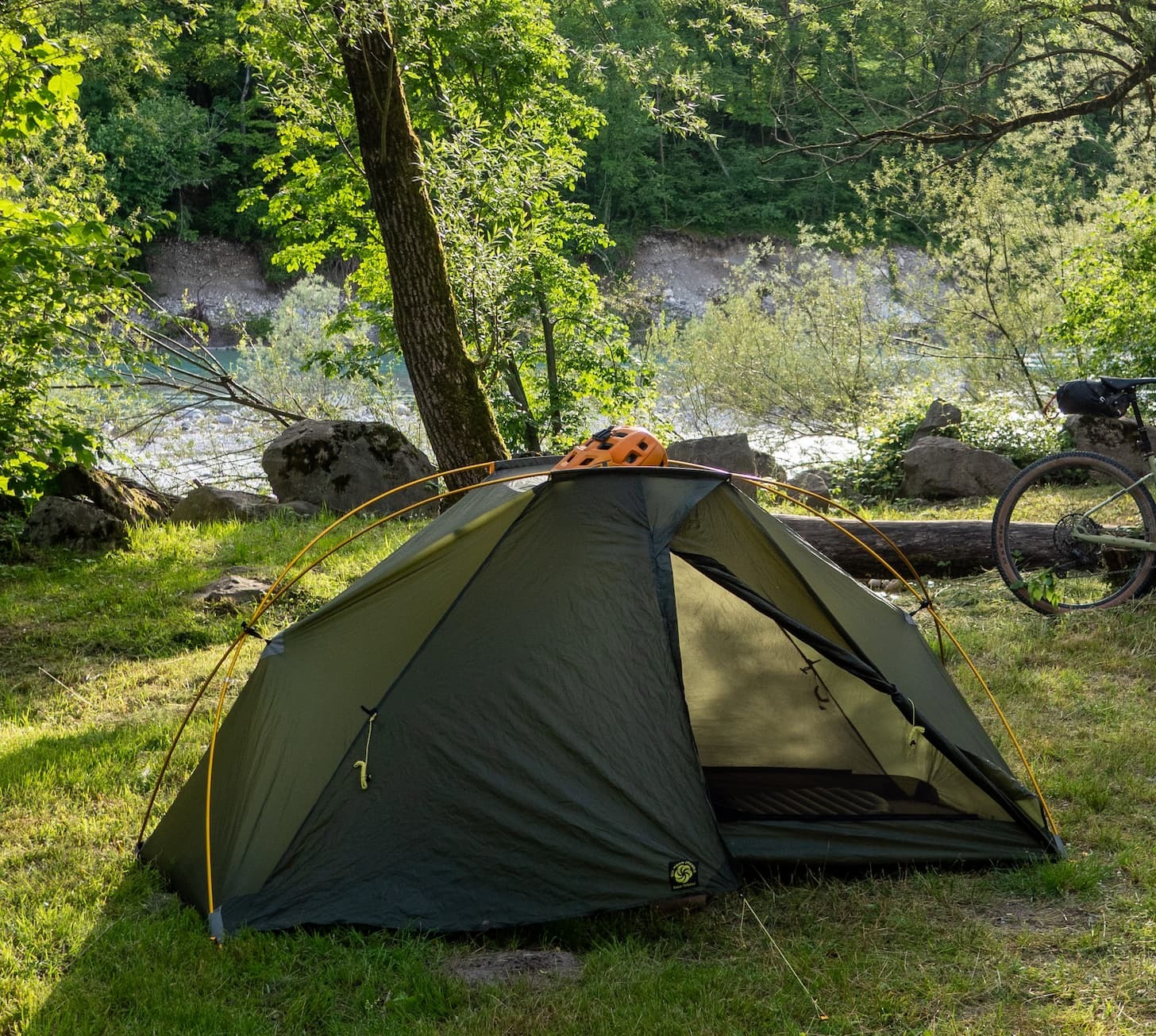 tent by river with bike helmet