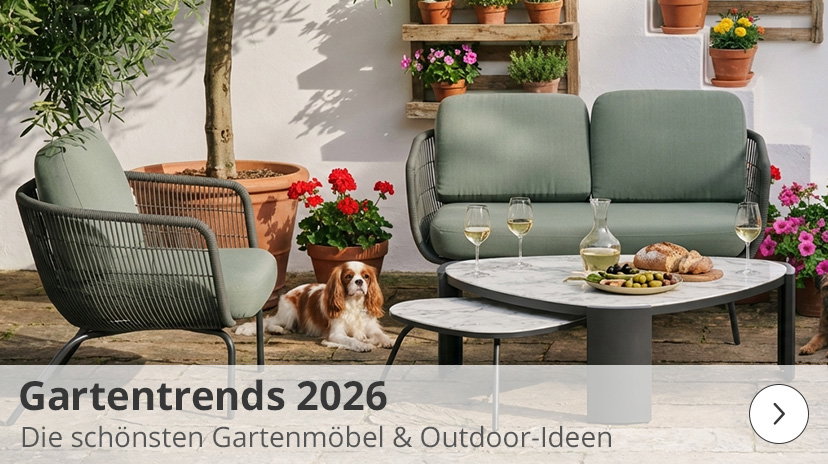 Werbegrafik mit der Aufschrift „Gartentrends 2026 – Die schönsten Gartenmöbel & Outdoor-Ideen“ vor einer mediterranen Terrassenkulisse: Im Mittelpunkt steht eine moderne Outdoor-Lounge mit olivgrünen Polstern und dunkelgrauem Seilgeflecht, bestehend aus einem Sofa und einem Sessel. Davor sind zwei ineinander schiebbare Couchtische mit weißer Marmoroptik-Platte platziert, auf denen Weingläser, eine Karaffe und Snacks angerichtet sind. Ein kleiner King Charles Spaniel Hund liegt entspannt auf dem Boden neben den Möbeln, umgeben von Pflanztöpfen.