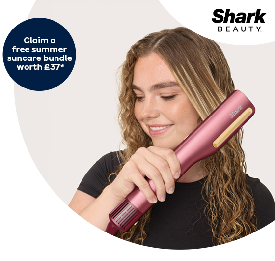 A woman straightening her hair with the pink Shark hair straightener + dryer