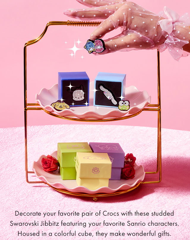Crocs Jibbitz™ with Swarovski® Crystals posed with a lace gloved hand. | Add a Little Sparkle! | Decorate your favorite pair of Crocs with these studded Swarovski Jibbitz featuring your favorite Sanrio characters. Housed in a colorful cube, they make wonderful gifts.