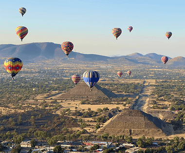 Hot air balloons over pyramids and mountains.