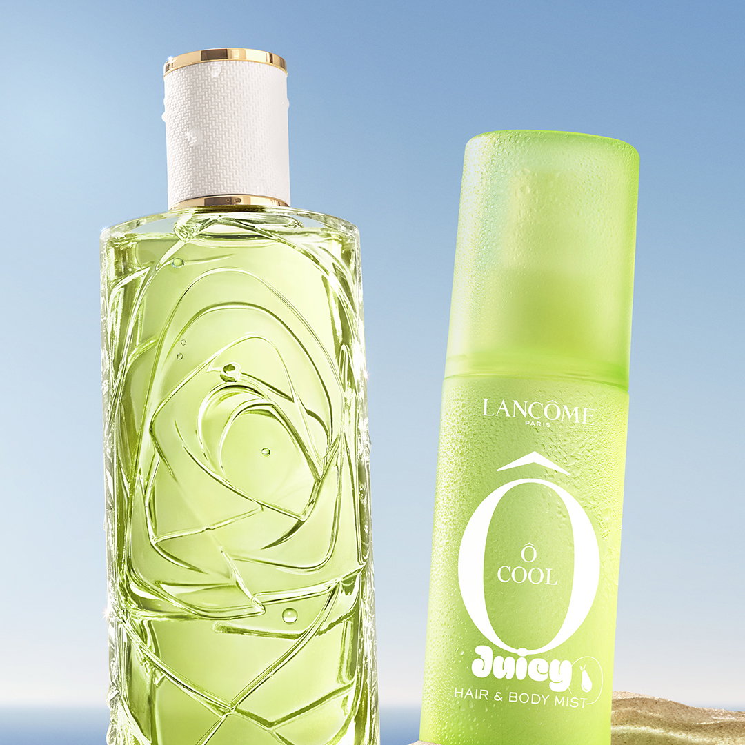 La nuova mist Ô Cool e l'iconico profumo Ô de Lancôme, entrambi verdi, affiancati su una spiaggia sabbiosa.
