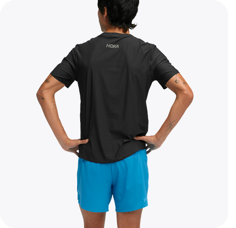 An image of a person from the front wearing the Airolite Short Sleeve, a HOKA run hat, a close up of a person zipping up the GlideTech Top, and a close up of a person wearing the Glide Shorts pulling their shirt up slightly.