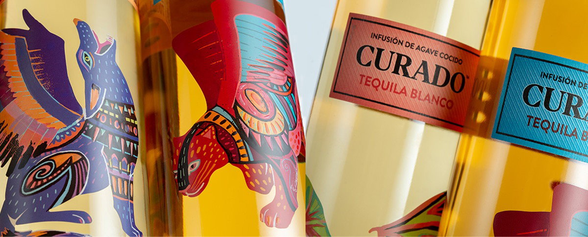 Close-up of Curado tequila bottles with colourful animal illustrations and blue and red labels on golden liquid