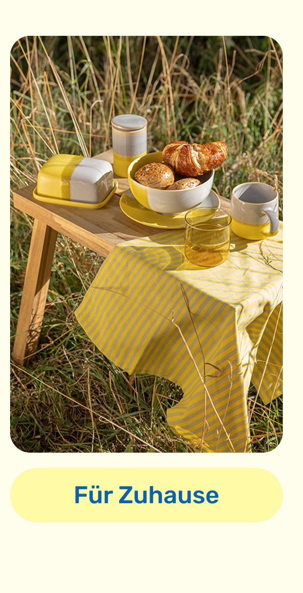 Hocker im Gras mit gelbem Frühstücksgeschirr. Button: Produkte für Zuhause.