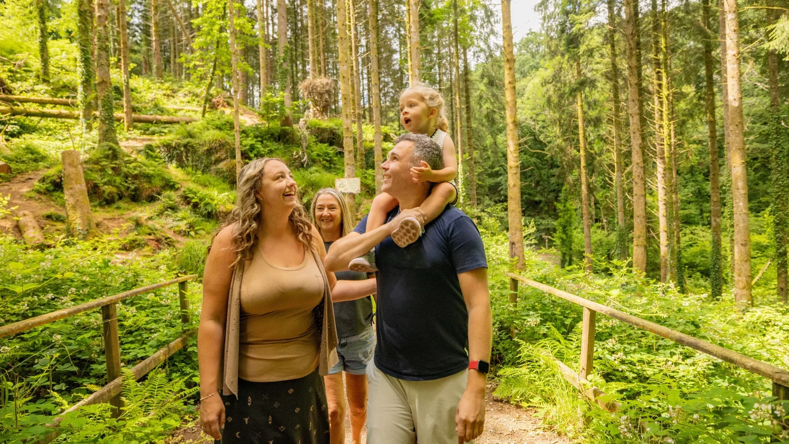 Family walking through bluestone's woods with daughter on her dads shoulders