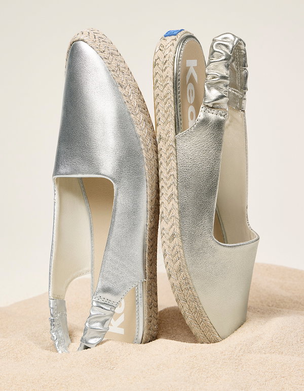 The Point Slingback Metallic Leather Jute Foxing in silver shown upright on a sandy surface.