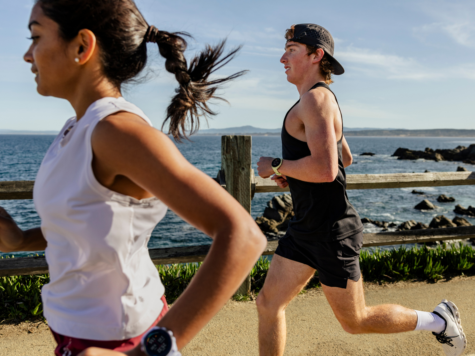 Two people running next to the beach wearing Garmin watches