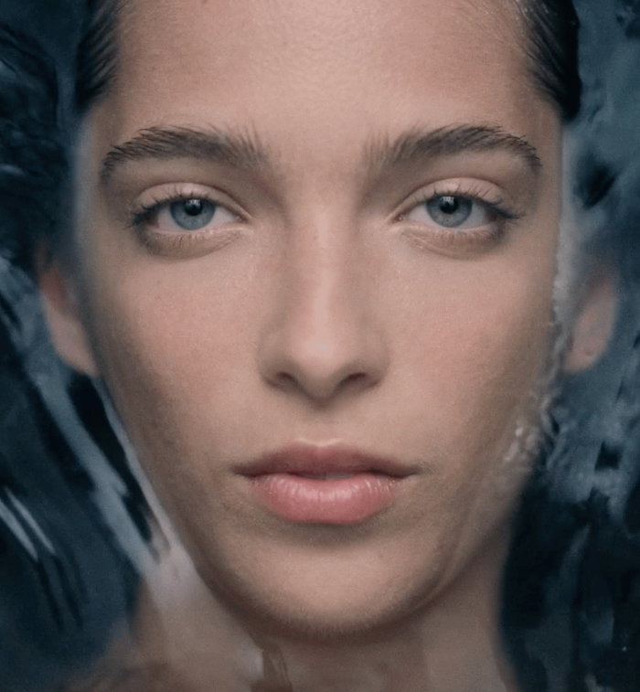 An image of a model's face with water in the background