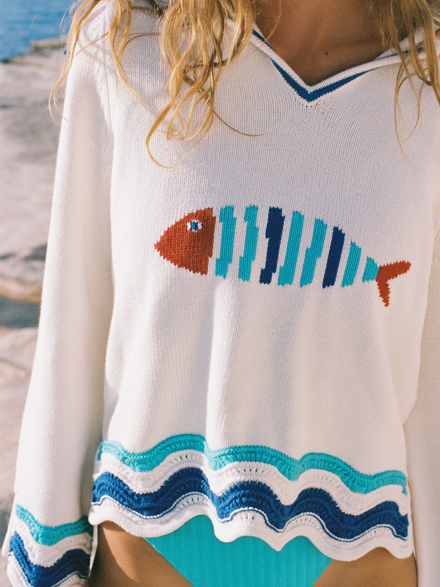 Woman wearing white sweater with fish detail